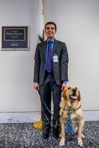 Laurel stands with his guide dog in a white office