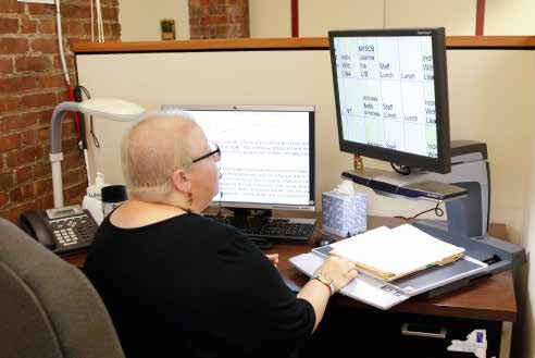Lady working dual monitors on her small desk