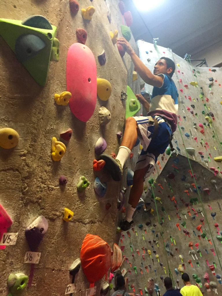 young man top roping a climbing wall