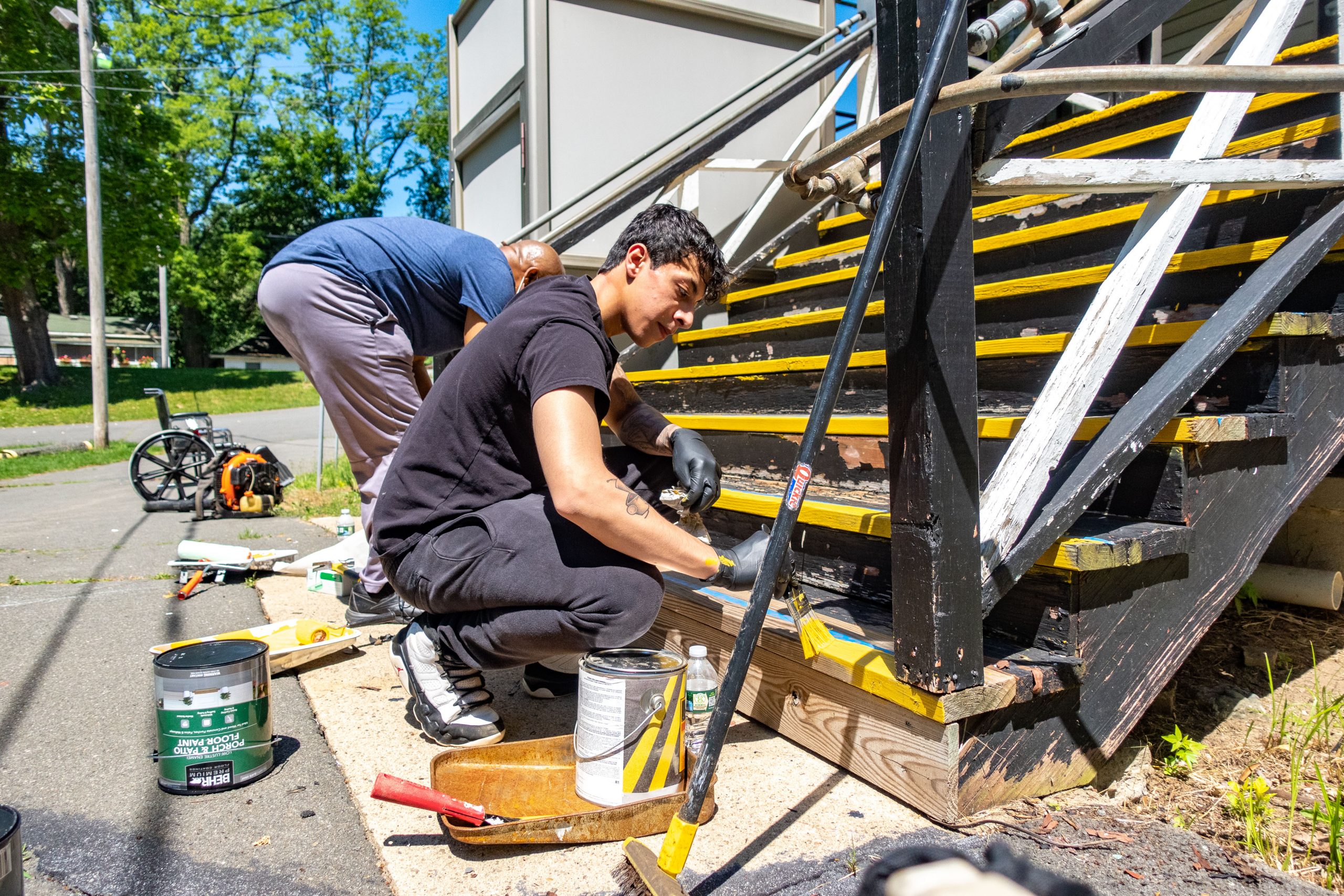 Two volunteers paint bright yellow lines on black steps at VISIONS Center on Blindness.