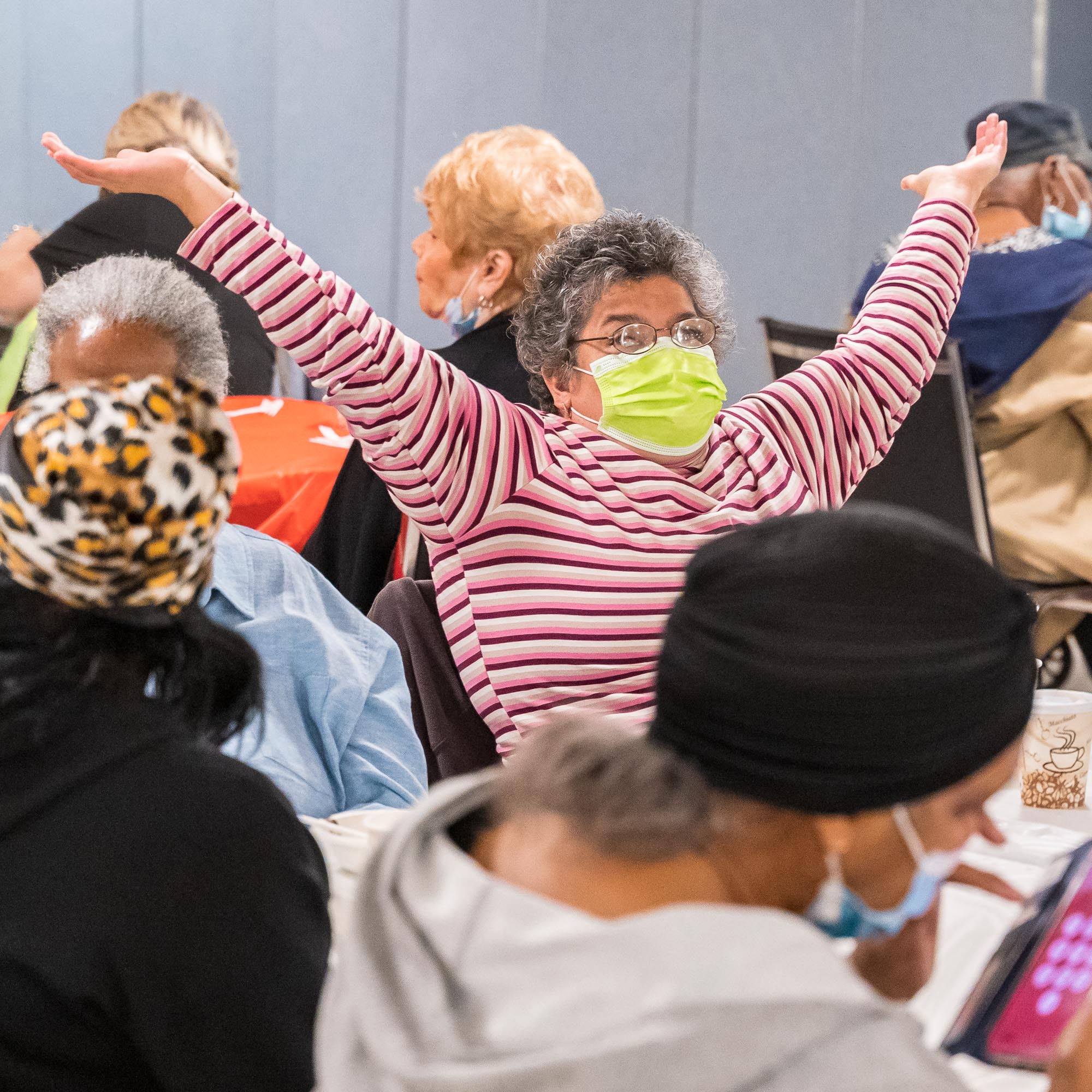 Photo of an older woman raising her hands in the air out of excitement.