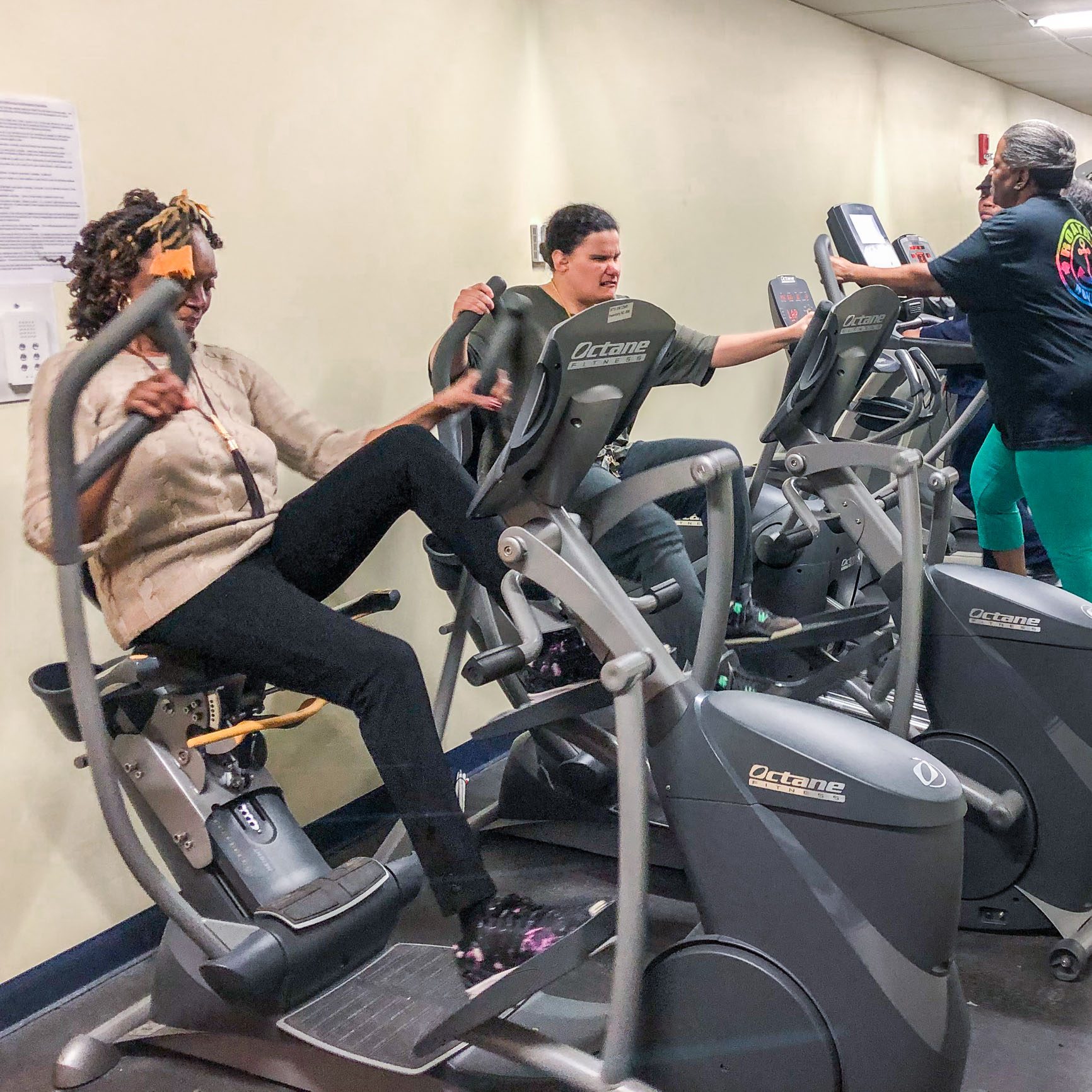 Photo of participants using cardio exercise machines in a gym.