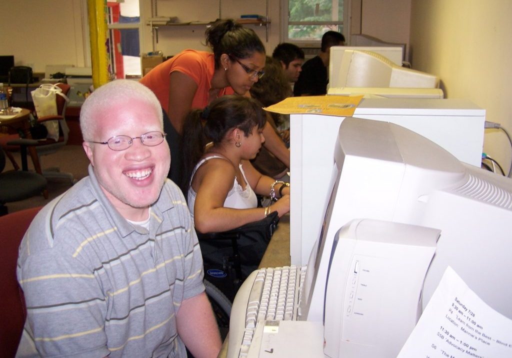 young man taking a break from assistive tech learning to smile at camera